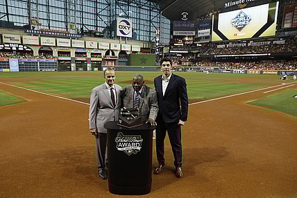 Oct 23, 2019; Houston, TX, USA; Hall of Fame member Hank Aaron (at podium) is joined by Major League Baseball chief baseball officer Joe Torre (left) and Milwaukee Brewers outfielder Christian Yelich (right) for a presentation of the 2019 Hank Aaron Awards before the first inning of game two of the 2019 World Series between the Houston Astros and the Washington Nationals at Minute Maid Park. Mandatory Credit: Matt Slocum/Pool Photo via USA TODAY Sports