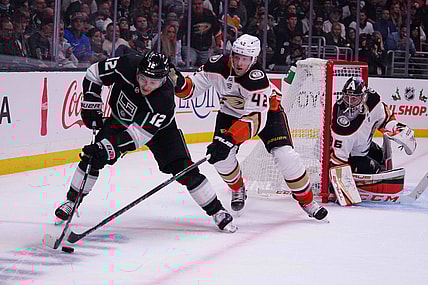 Nov 30, 2021; Los Angeles, California, USA; LA Kings center Trevor Moore (12) and Anaheim Ducks defenseman Josh Manson (42) battle for the puck as Ducks goaltender John Gibson (36) watches in the second period at Staples Center. Mandatory Credit: Kirby Lee-USA TODAY Sports