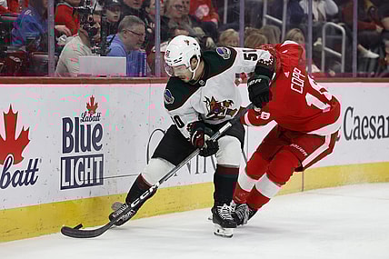 Mar 14, 2024; Detroit, Michigan, USA;  Arizona Coyotes defenseman Sean Durzi (50) and Detroit Red Wings center Andrew Copp (18) battle for the puck in the second period at Little Caesars Arena. Mandatory Credit: Rick Osentoski-USA TODAY Sports