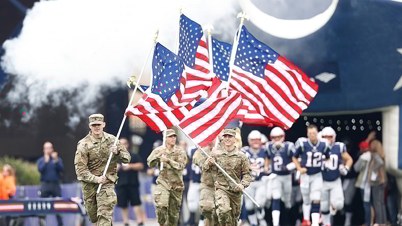 United States military members raise flag ahead of NFL game.