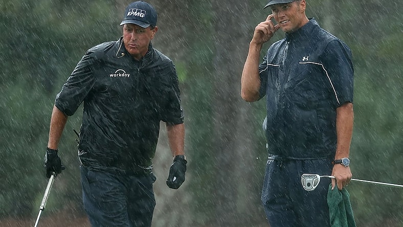 May 24, 2020; Hobe Sound, FL, USA; Phil Mickelson and NFL player Tom Brady of the Tampa Bay Buccaneers react on the 13th green in the rain during The Match: Champions for Charity golf round at the Medalist Golf Club.  Mandatory Credit: Handout Photo by Getty Images for The Match via USA TODAY Sports