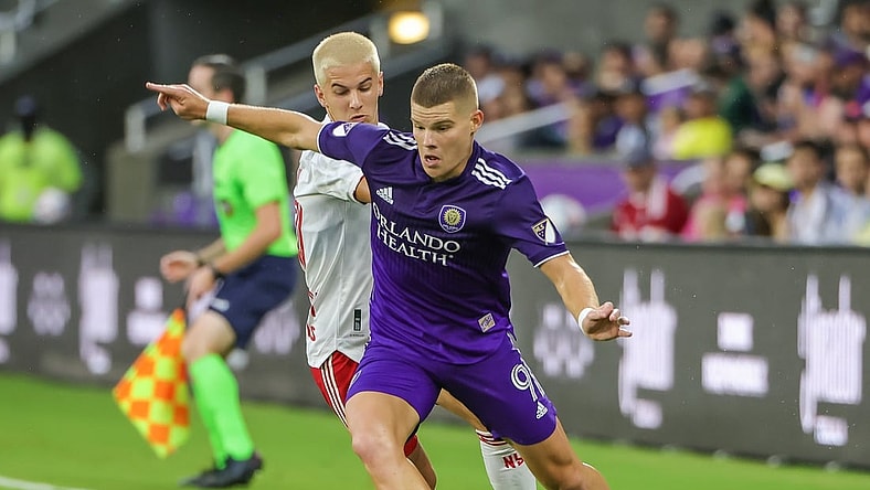 Jul 3, 2021; Orlando, Florida, USA; Orlando City forward Chris Mueller (9) kicks the ball in front of New York Red Bulls defender John Tolkin (47) during the first half at Orlando City Stadium. Mandatory Credit: Mike Watters-USA TODAY Sports