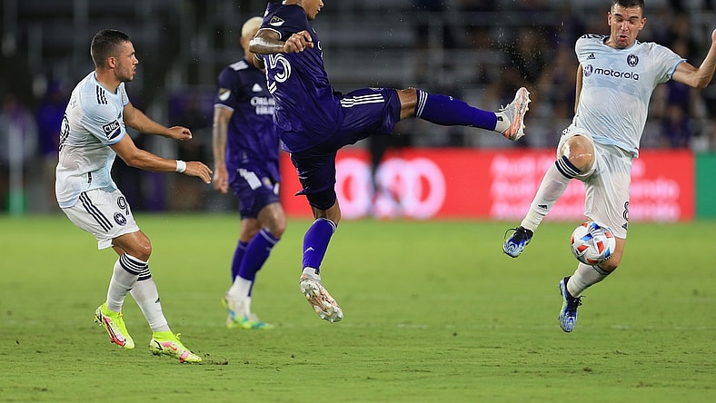 Aug 21, 2021; Orlando, Florida, USA; Orlando City defender Antonio Carlos (25) controls the ball between Chicago Fire midfielder Stanislav Ivanov (99) and midfielder Luka Stojanovic (8) at Orlando City Stadium. Mandatory Credit: Matt Stamey-USA TODAY Sports