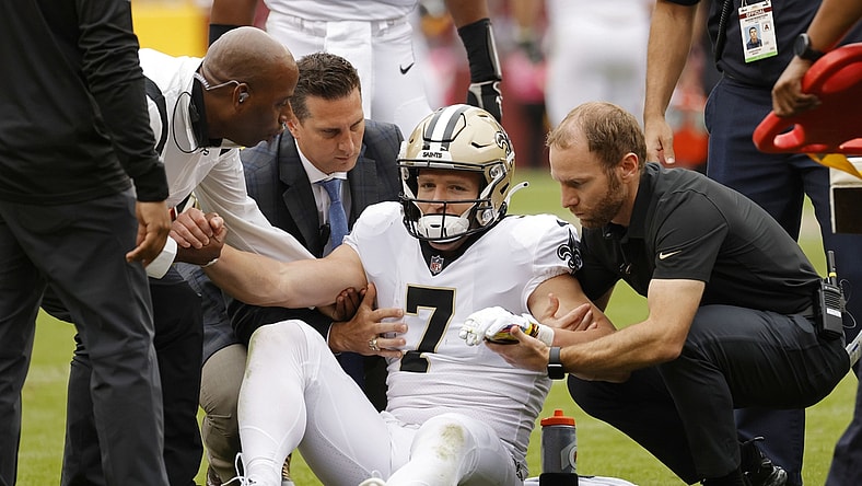 Oct 10, 2021; Landover, Maryland, USA; New Orleans Saints wide receiver Taysom Hill (7) is helped to his feet after being injured against the Washington Football Team during the second quarter at FedExField. Mandatory Credit: Geoff Burke-USA TODAY Sports