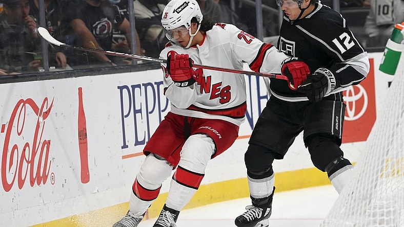 Nov 20, 2021; Los Angeles, California, USA;  Carolina Hurricanes defenseman Ethan Bear (25) and Los Angeles Kings center Trevor Moore (12) battle for the puck in the second period at Staples Center. Mandatory Credit: Jayne Kamin-Oncea-USA TODAY Sports