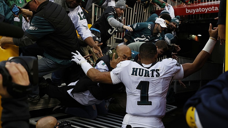 Jan 2, 2022; Landover, Maryland, USA; Fans fall from the stands after a railing gives way as Philadelphia Eagles quarterback Jalen Hurts (1) leaves the field after the Eagles' game against the Washington Football Team at FedExField. Mandatory Credit: Geoff Burke-USA TODAY Sports