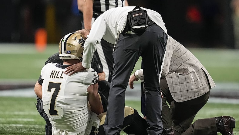 Jan 9, 2022; Atlanta, Georgia, USA; New Orleans Saints quarterback Taysom Hill (7) is checked after being injured running against the Atlanta Falcons during the first half at Mercedes-Benz Stadium. Mandatory Credit: Dale Zanine-USA TODAY Sports