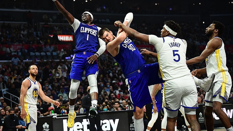 Feb 14, 2022; Los Angeles, California, USA; Los Angeles Clippers guard Reggie Jackson (1) moves to the basket as center Ivica Zubac (40) provides coverage against Golden State Warriors center Kevon Looney (5) during the first half at Crypto.com Arena. Mandatory Credit: Gary A. Vasquez-USA TODAY Sports