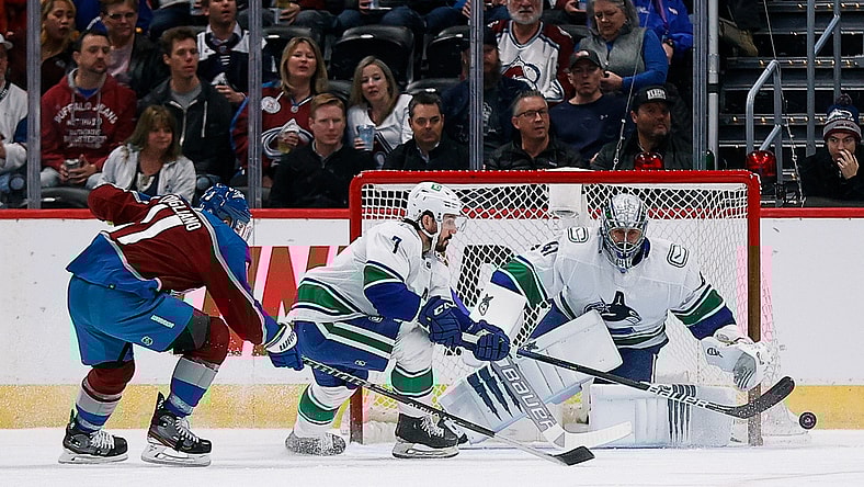 Mar 23, 2022; Denver, Colorado, USA; Vancouver Canucks center Nic Petan (7) and Colorado Avalanche center Andrew Cogliano (11) battle for the puck ahead of goaltender Jaroslav Halak (41) in the first period at Ball Arena. Mandatory Credit: Isaiah J. Downing-USA TODAY Sports