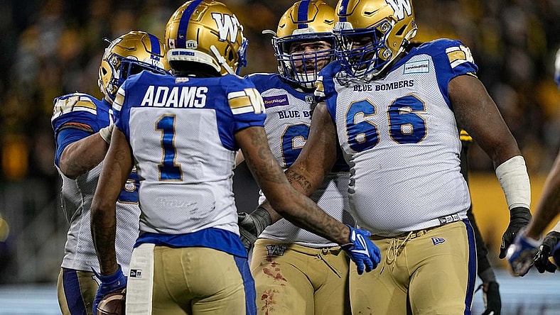Dec 12, 2021; Hamilton, Ontario, CAN; Winnipeg Blue Bombers offensive lineman Stanley Bryant (66) and offensive lineman Drew Desjarlais (61) congratulate wide receiver Darvin Adams (1) after scoring a touchdown in overtime against the Hamilton Tiger-Cats in the 108th Grey Cup football game at Tim Hortons Field. Mandatory Credit: John E. Sokolowski-USA TODAY Sports