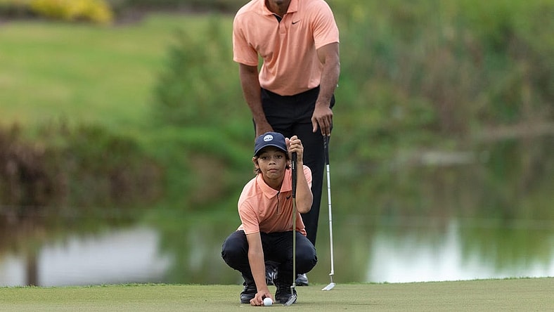Dec 18, 2021; Orlando, Florida, USA; Charlie Woods and his dad Tiger Woods lining his putt up on the 16th green during the first round of the PNC Championship golf tournament at Grande Lakes Orlando Course. Mandatory Credit: Jeremy Reper-USA TODAY Sports