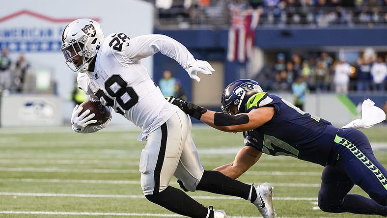Nov 27, 2022; Seattle, Washington, USA; Las Vegas Raiders running back Josh Jacobs (28) breaks a tackle attempt by Seattle Seahawks linebacker Cody Barton (57) after making a reception during the fourth quarter at Lumen Field. Mandatory Credit: Joe Nicholson-USA TODAY Sports