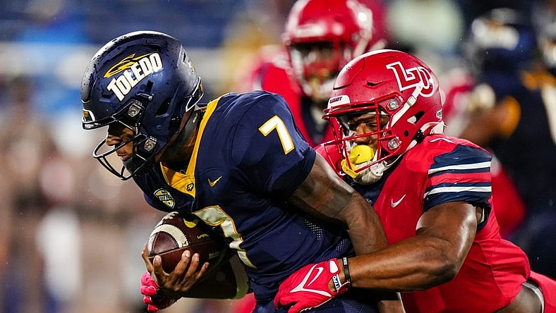 Dec 20, 2022; Boca Raton, Florida, USA; Liberty Flames linebacker Mike Smith Jr. (7) tackles Toledo Rockets quarterback Dequan Finn (7) during the first quarter in the 2022 Boca Raton Bowl at FAU Stadium. Mandatory Credit: Rich Storry-USA TODAY Sports