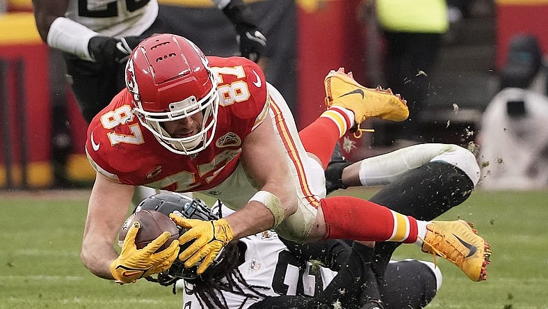Jan 21, 2023; Kansas City, Missouri, USA; Kansas City Chiefs tight end Travis Kelce (87) moves the ball ahead of Jacksonville Jaguars safety Rayshawn Jenkins (2) during the first half in the AFC divisional round game at GEHA Field at Arrowhead Stadium. Mandatory Credit: Denny Medley-USA TODAY Sports