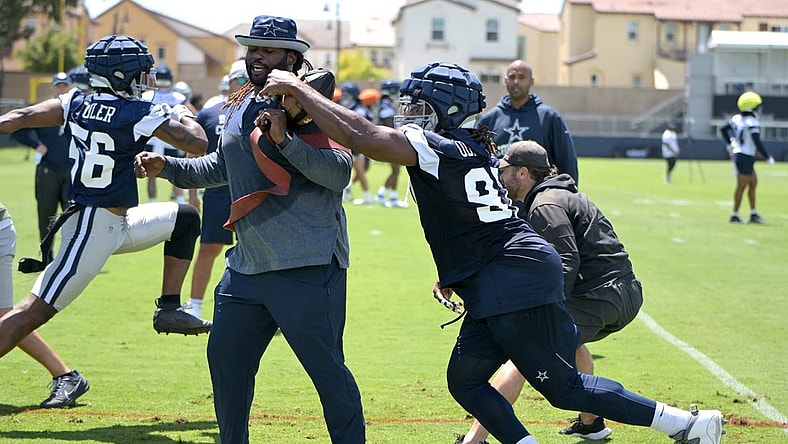 Jul 26, 2023; Oxnard, CA, USA;  Dallas Cowboys defensive end DeMarcus Lawrence (90) reaches around assistant defensive line coach Sharrif Floyd during training camp drills at River Ridge Playing Fields in Oxnard, CA. Mandatory Credit: Jayne Kamin-Oncea-USA TODAY Sports
