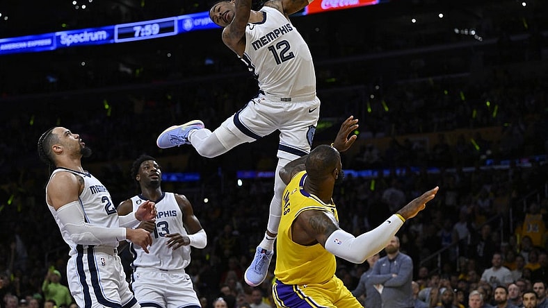 Apr 28, 2023; Los Angeles, California, USA; Memphis Grizzlies guard Ja Morant (12) hangs on the rim to avoid landing on Los Angeles Lakers forward LeBron James (6) after a dunk in the first quarter of game six of the 2023 NBA playoffs at Crypto.com Arena. Mandatory Credit: Jayne Kamin-Oncea-USA TODAY Sports