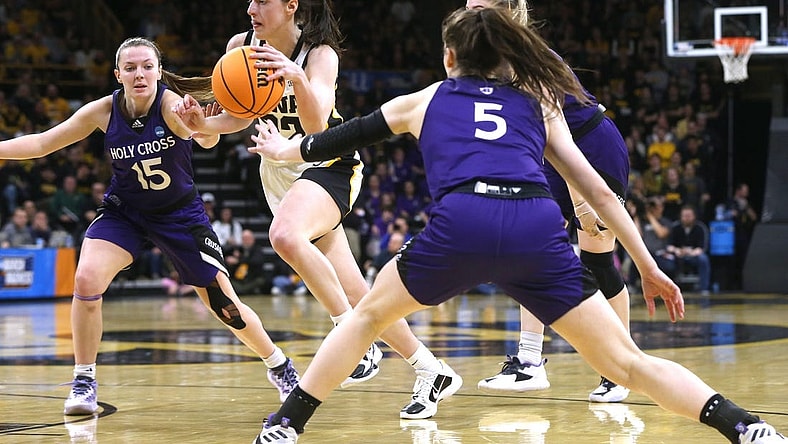 Iowa’s Caitlin Clark (22) dribbles between a host of Holy Cross defenders in a first-round NCAA Tournament game Saturday, March 23, 2024 at Carver-Hawkeye Arena in Iowa City, Iowa.