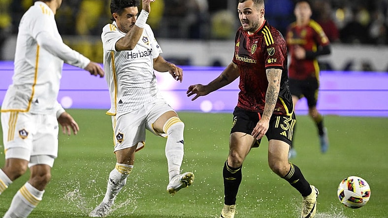 Mar 30, 2024; Carson, California, USA; LA Galaxy midfielder Gaston Brugman (5) battles for the ball against Seattle Sounders FC forward Jordan Morris (13) during the first half at Dignity Health Sports Park. Mandatory Credit: Alex Gallardo-USA TODAY Sports