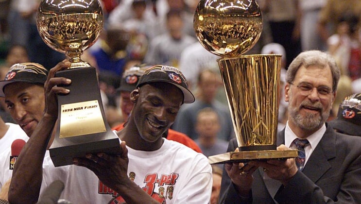 Michael Jordan holds the MVP trophy and coach Phil Jackson holds the championship trophy after the Bulls beat the Jazz to win their sixth title in 1998