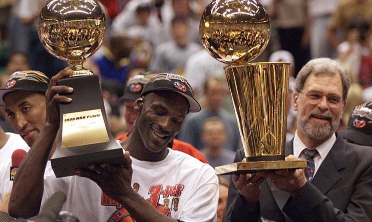 Michael Jordan holds the MVP trophy and coach Phil Jackson holds the championship trophy after the Bulls beat the Jazz to win their sixth title in 1998