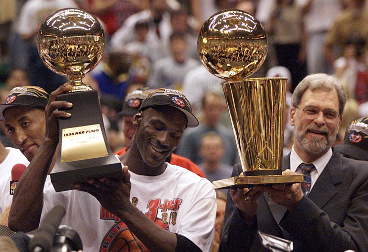 Michael Jordan holds the MVP trophy and coach Phil Jackson holds the championship trophy after the Bulls beat the Jazz to win their sixth title in 1998