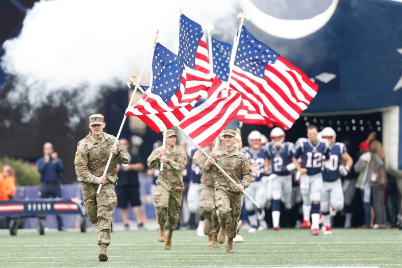 United States military members raise flag ahead of NFL game.