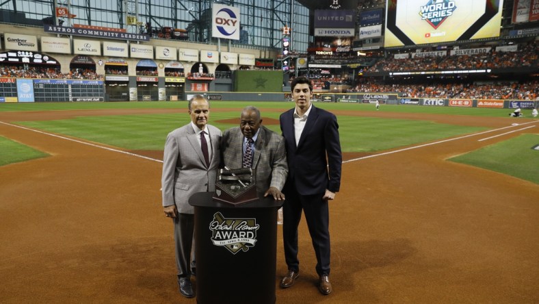 Oct 23, 2019; Houston, TX, USA; Hall of Fame member Hank Aaron (at podium) is joined by Major League Baseball chief baseball officer Joe Torre (left) and Milwaukee Brewers outfielder Christian Yelich (right) for a presentation of the 2019 Hank Aaron Awards before the first inning of game two of the 2019 World Series between the Houston Astros and the Washington Nationals at Minute Maid Park. Mandatory Credit: Matt Slocum/Pool Photo via USA TODAY Sports