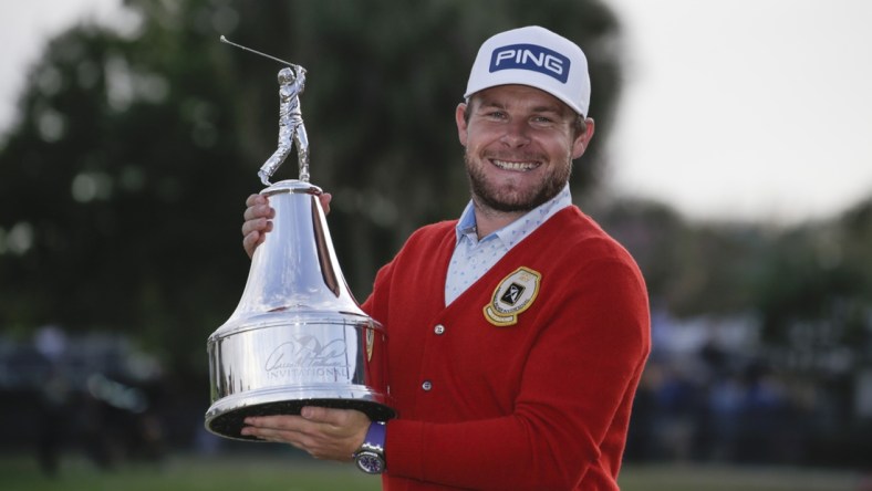 Mar 8, 2020; Orlando, Florida, USA; Tyrrell Hatton wears a red alpaca cardigan sweater given to the winner as he holds the champions trophy after winning the Arnold Palmer Invitational golf tournament at Bay Hill Club & Lodge. Mandatory Credit: Reinhold Matay-USA TODAY Sports