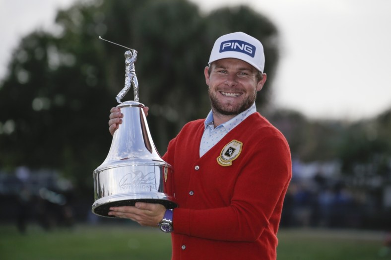 Mar 8, 2020; Orlando, Florida, USA; Tyrrell Hatton wears a red alpaca cardigan sweater given to the winner as he holds the champions trophy after winning the Arnold Palmer Invitational golf tournament at Bay Hill Club & Lodge. Mandatory Credit: Reinhold Matay-USA TODAY Sports