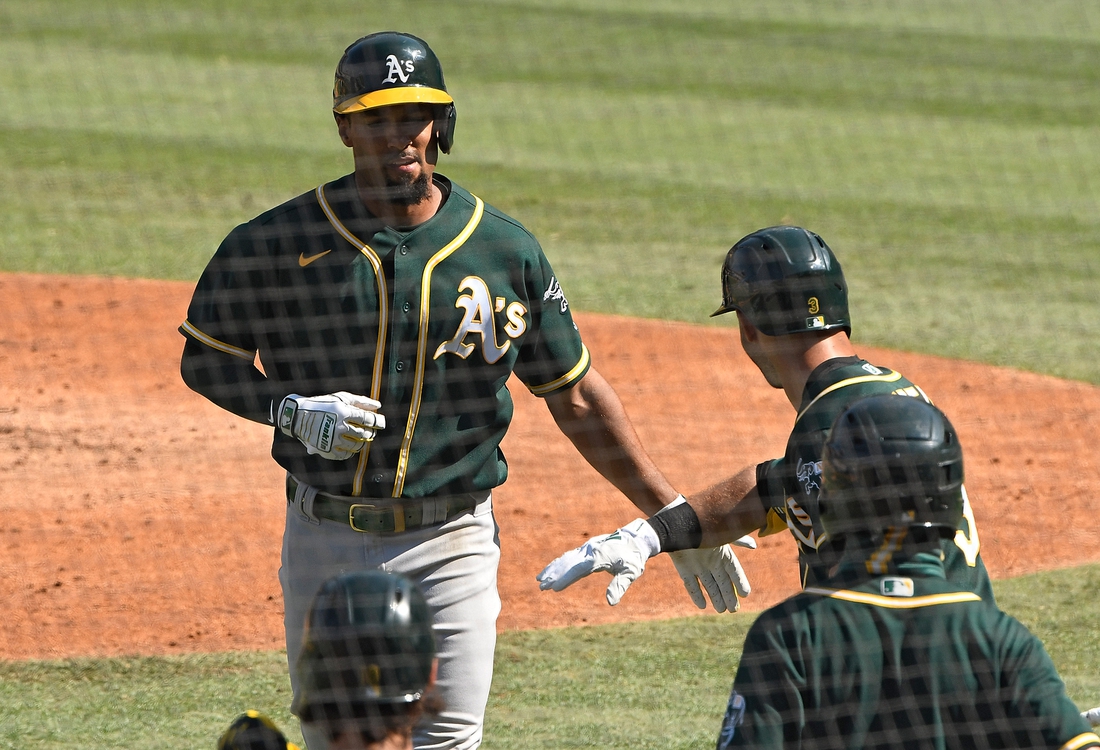 Oct 7, 2020; Los Angeles, California, USA; Oakland Athletics shortstop Marcus Semien (10) is congratulated by second baseman Tommy La Stella (3) after hitting a solo home run off of Houston Astros starting pitcher Jose Urquidy (not pictured) during the fifth inning in game three of the 2020 ALDS at Dodger Stadium. Mandatory Credit: Robert Hanashiro-USA TODAY Sports