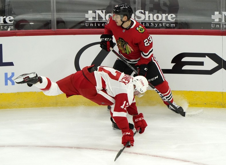 Jan 22, 2021; Chicago, Illinois, USA; Detroit Red Wings defenseman Filip Hronek (17) trips over Chicago Blackhawks left wing Philipp Kurashev (23) during the second period at the United Center. Mandatory Credit: Mike Dinovo-USA TODAY Sports