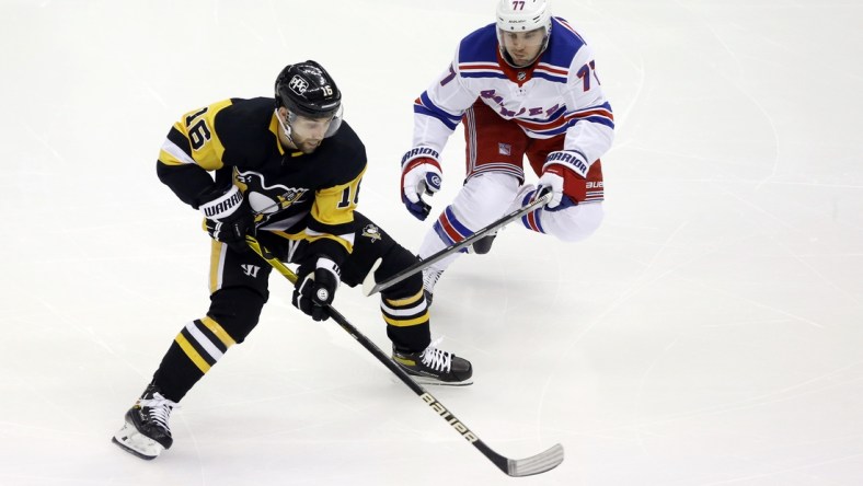 Jan 24, 2021; Pittsburgh, Pennsylvania, USA;  Pittsburgh Penguins left wing Jason Zucker (16) moves the puck against New York Rangers defenseman Tony DeAngelo (77) during the first period at the PPG Paints Arena. Mandatory Credit: Charles LeClaire-USA TODAY Sports