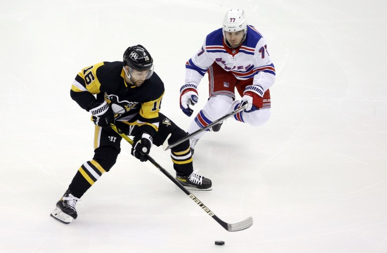 Jan 24, 2021; Pittsburgh, Pennsylvania, USA;  Pittsburgh Penguins left wing Jason Zucker (16) moves the puck against New York Rangers defenseman Tony DeAngelo (77) during the first period at the PPG Paints Arena. Mandatory Credit: Charles LeClaire-USA TODAY Sports