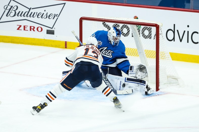 Jan 24, 2021; Winnipeg, Manitoba, CAN;  Winnipeg Jets goalie Laurent Brossoit (30) makes a save on a shot by Edmonton Oilers forward Jesse Puljujarvi (13) during the first period at Bell MTS Place. Mandatory Credit: Terrence Lee-USA TODAY Sports