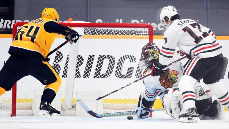 Jan 26, 2021; Nashville, Tennessee, USA; Chicago Blackhawks goaltender Malcolm Subban (30) covers a puck in the crease against  Nashville Predators center Mikael Granlund (64) during the second period at Bridgestone Arena. Mandatory Credit: Christopher Hanewinckel-USA TODAY Sports