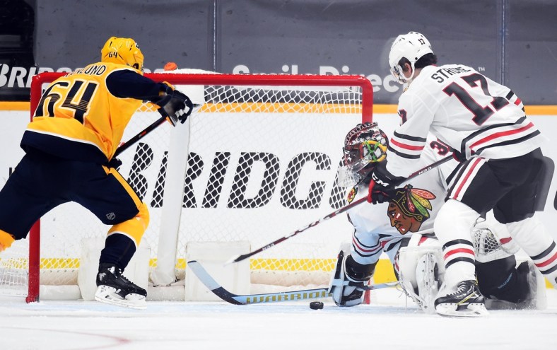 Jan 26, 2021; Nashville, Tennessee, USA; Chicago Blackhawks goaltender Malcolm Subban (30) covers a puck in the crease against  Nashville Predators center Mikael Granlund (64) during the second period at Bridgestone Arena. Mandatory Credit: Christopher Hanewinckel-USA TODAY Sports