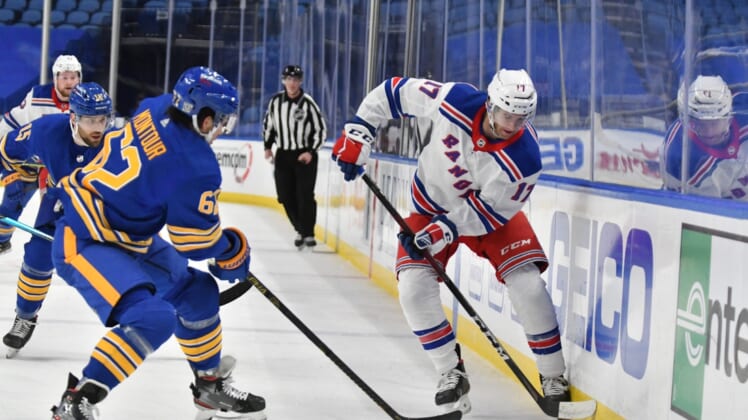 Jan 28, 2021; Buffalo, New York, USA; New York Rangers center Kevin Rooney (17) and Buffalo Sabres defenseman Brandon Montour (62) vie for the puck in the first period at KeyBank Center. Mandatory Credit: Mark Konezny-USA TODAY Sports