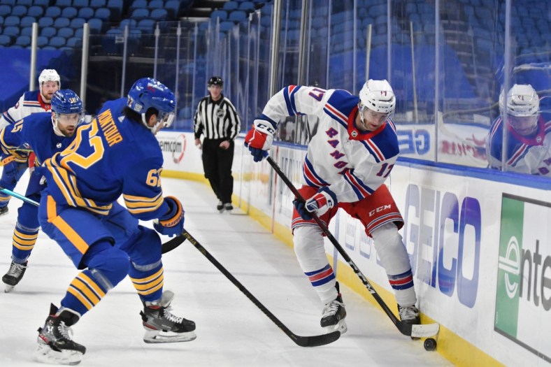 Jan 28, 2021; Buffalo, New York, USA; New York Rangers center Kevin Rooney (17) and Buffalo Sabres defenseman Brandon Montour (62) vie for the puck in the first period at KeyBank Center. Mandatory Credit: Mark Konezny-USA TODAY Sports