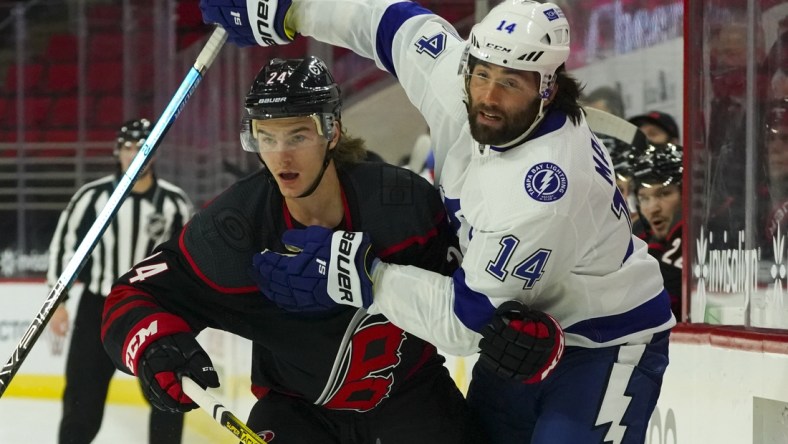 Jan 28, 2021; Raleigh, North Carolina, USA;  Carolina Hurricanes defensemen Jake Bean (24) and Tampa Bay Lightning left wing Pat Maroon (14 watch the play during the first period at PNC Arena. Mandatory Credit: James Guillory-USA TODAY Sports