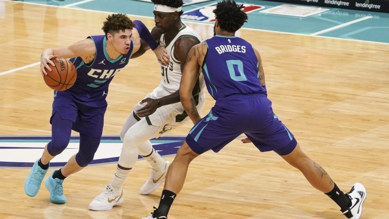 Jan 30, 2021; Charlotte, North Carolina, USA; Charlotte Hornets guard LaMelo Ball (2) drives past Milwaukee Bucks guard Jrue Holiday (21) with help from forward Miles Bridges (0) during the first quarter at Spectrum Center. Mandatory Credit: Jim Dedmon-USA TODAY Sports