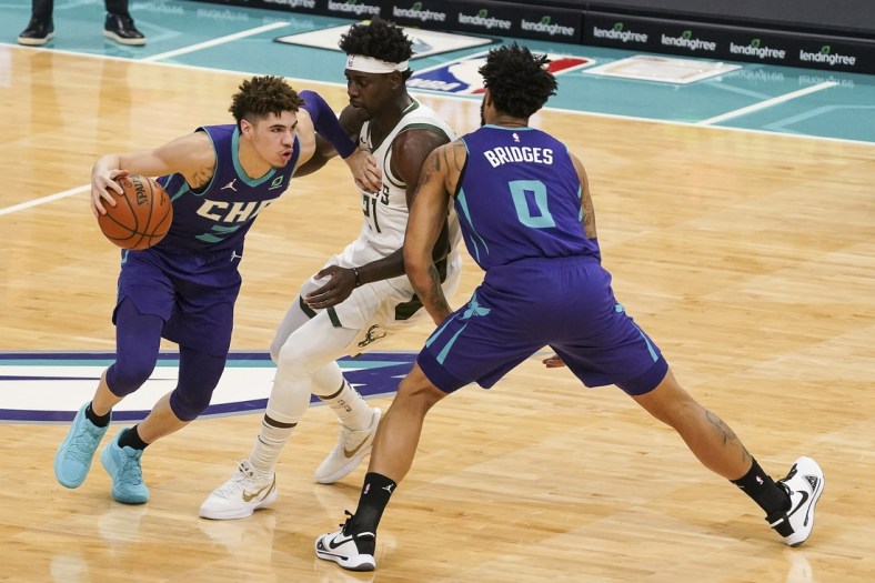 Jan 30, 2021; Charlotte, North Carolina, USA; Charlotte Hornets guard LaMelo Ball (2) drives past Milwaukee Bucks guard Jrue Holiday (21) with help from forward Miles Bridges (0) during the first quarter at Spectrum Center. Mandatory Credit: Jim Dedmon-USA TODAY Sports