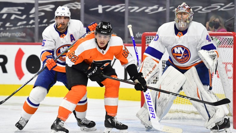 Jan 30, 2021; Philadelphia, Pennsylvania, USA; New York Islanders right wing Cal Clutterbuck (15) checks Philadelphia Flyers center Connor Bunnaman (82) in front of goaltender Semyon Varlamov (40) during the second period at Wells Fargo Center. Mandatory Credit: Eric Hartline-USA TODAY Sports