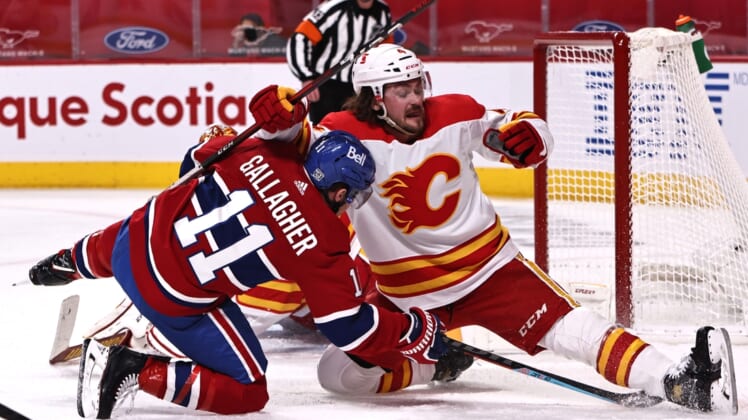 Jan 30, 2021; Montreal, Quebec, CAN; Calgary Flames defenseman Rasmus Andersson (4) and Montreal Canadiens right wing Brendan Gallagher (11) fall in front of goaltender Jacob Markstrom (25) during the second period at Bell Centre. Mandatory Credit: Jean-Yves Ahern-USA TODAY Sports