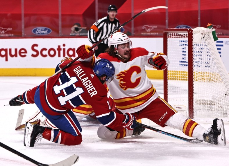 Jan 30, 2021; Montreal, Quebec, CAN; Calgary Flames defenseman Rasmus Andersson (4) and Montreal Canadiens right wing Brendan Gallagher (11) fall in front of goaltender Jacob Markstrom (25) during the second period at Bell Centre. Mandatory Credit: Jean-Yves Ahern-USA TODAY Sports
