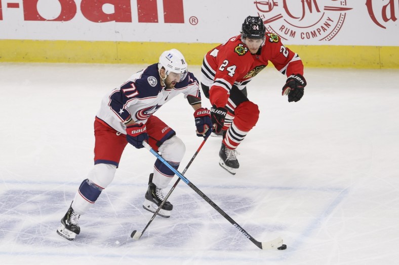 Jan 31, 2021; Chicago, Illinois, USA; Columbus Blue Jackets left wing Nick Foligno (71) keeps the puck away from Chicago Blackhawks center Pius Suter (24) during the first period at United Center. Mandatory Credit: Kamil Krzaczynski-USA TODAY Sports