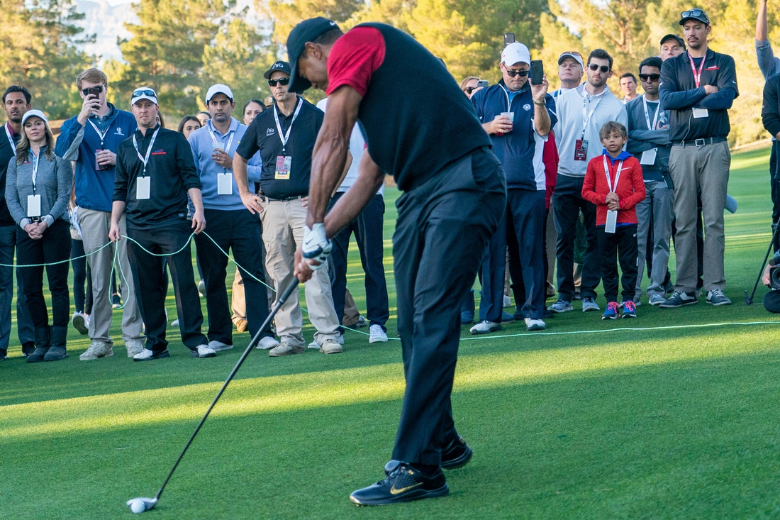 November 23, 2018; Las Vegas, NV, USA; Charlie Woods (red long sleeve) watches father Tiger Woods (left) hit his fairway shot on the 16th hole during The Match: Tiger vs Phil golf match at Shadow Creek Golf Course. Mandatory Credit: Kyle Terada-USA TODAY Sports