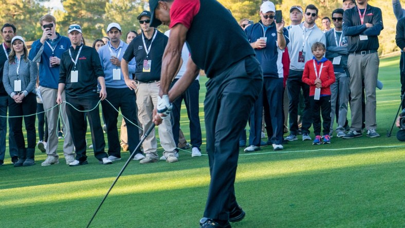 November 23, 2018; Las Vegas, NV, USA; Charlie Woods (red long sleeve) watches father Tiger Woods (left) hit his fairway shot on the 16th hole during The Match: Tiger vs Phil golf match at Shadow Creek Golf Course. Mandatory Credit: Kyle Terada-USA TODAY Sports