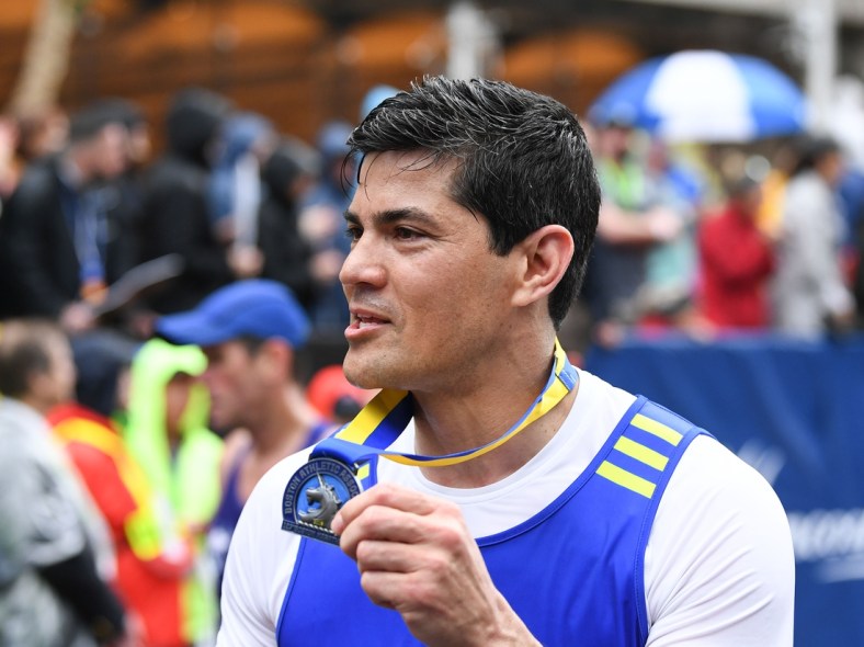 Apr 15, 2019; Boston, MA, USA; ESPN analyst and former New England Patriots player Tedy Bruschi holds up his medal after finishing the 2019 Boston Marathon. Mandatory Credit: Brian Fluharty-USA TODAY Sports