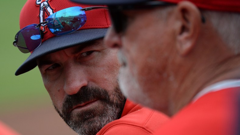 Mar 10, 2020; Peoria, Arizona, USA; Los Angeles Angels pitching coach Mickey Callaway (left) talks with manager Joe Maddon during the second inning of a spring training game against the Seattle Mariners at Peoria Stadium. Mandatory Credit: Joe Camporeale-USA TODAY Sports