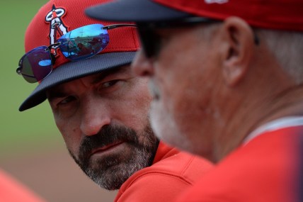 Mar 10, 2020; Peoria, Arizona, USA; Los Angeles Angels pitching coach Mickey Callaway (left) talks with manager Joe Maddon during the second inning of a spring training game against the Seattle Mariners at Peoria Stadium. Mandatory Credit: Joe Camporeale-USA TODAY Sports